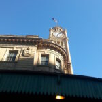 Clock tower of Sydney Central Station rising above the station awning against a clear blue sky.